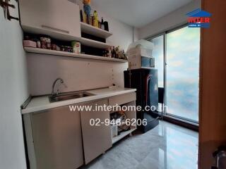 Compact kitchen with white cabinetry and natural light