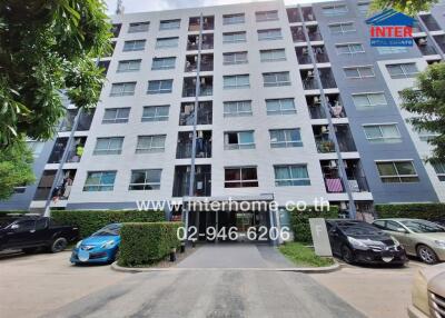 Exterior view of a modern residential apartment building with parked cars