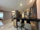 Modern kitchen with open floor plan featuring a breakfast bar, sleek shelving, and ample lighting