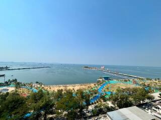 Scenic ocean view from a high-rise apartment balcony showing a beachfront and bustling port