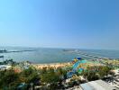 Scenic ocean view from a high-rise apartment balcony showing a beachfront and bustling port