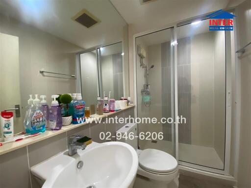 Modern bathroom with reflected mirror, shower cabin, and essential toiletries