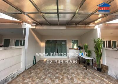 Spacious tiled patio with partial roofing and door leading inside