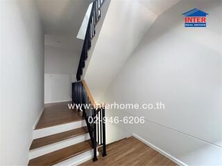 Modern staircase with wooden steps and black metal railing in a well-lit home