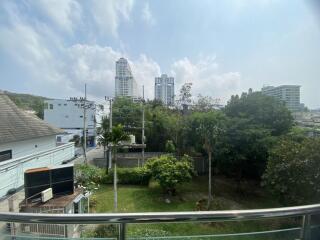 City view from residential balcony showcasing lush greenery and surrounding buildings