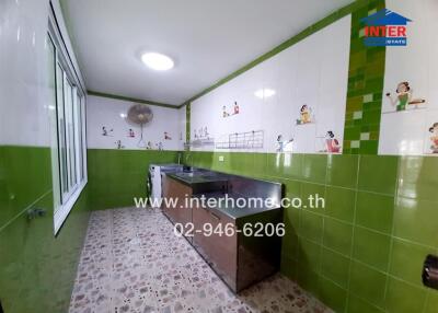 Spacious kitchen with green tiling and ample natural light