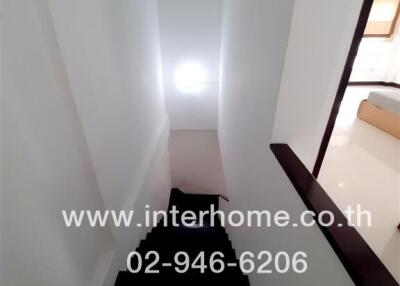 Modern white staircase with wooden handrails leading downstairs
