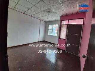 Spacious unfurnished room with large windows and pink door