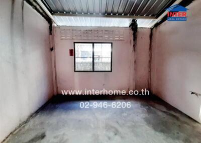 Empty industrial room with a single window and concrete flooring