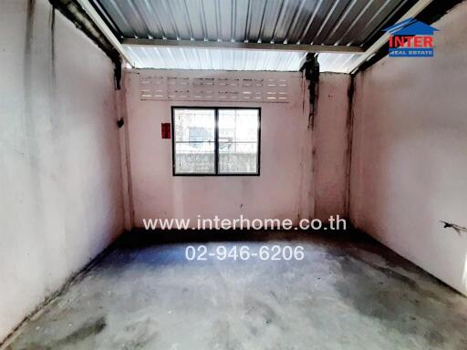 Empty industrial room with a single window and concrete flooring