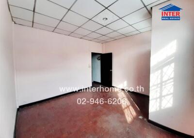 Empty room with hardwood flooring and suspended ceiling