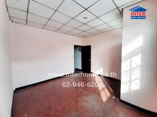 Empty room with hardwood flooring and suspended ceiling