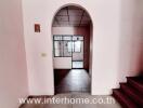 Spacious entrance hall leading to the main door of the house with visible staircase and tiled flooring