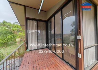 Spacious covered balcony with wooden flooring and glass walls