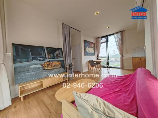 Modern and well-lit living room with large TV and balcony access