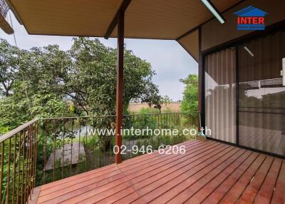 Spacious balcony with wooden flooring and a view of greenery