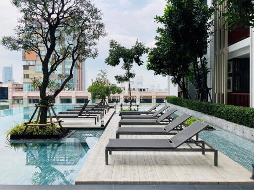 Luxurious outdoor pool area with lounge chairs and urban backdrop