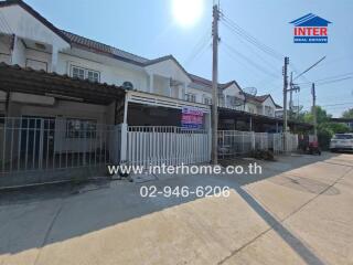 Exterior view of a row of townhouses with a for sale sign