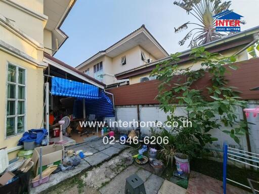 Exterior view of a cluttered house with garden area