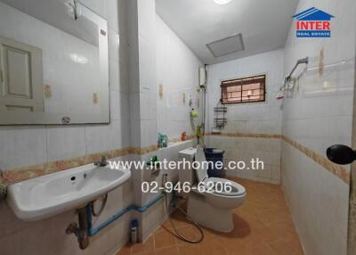 Spacious tiled bathroom with white fixtures