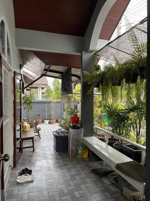 Spacious covered porch area with seating and lush greenery