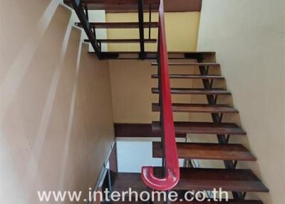 Wooden staircase in a building with a red handrail