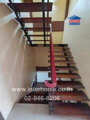 Wooden staircase in a building with a red handrail