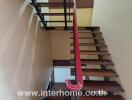 Wooden staircase in a building with a red handrail