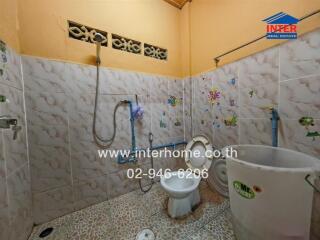 Compact tiled bathroom with toilet and shower