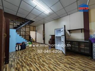 Spacious interior of a building showing a staircase, storage areas, and tiled flooring