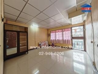Spacious living room with large windows and tiled flooring