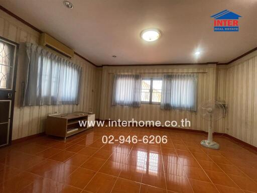 Spacious living room with large windows and tiled flooring