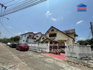 Exterior view of a residential property with multiple houses and parked cars under a clear blue sky