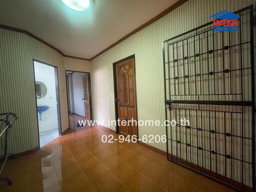 Interior view of a residential hallway featuring striped wallpaper and traditional wooden doors