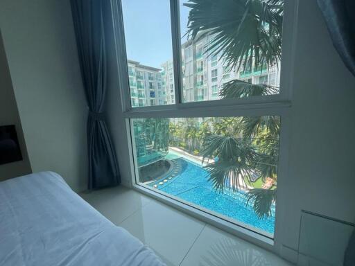 Bright bedroom with a view of a pool and lush greenery