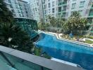 Luxurious apartment complex with large swimming pool and lush greenery