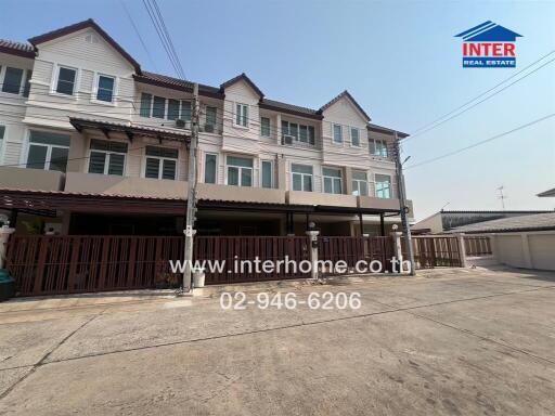 Exterior view of a row of modern townhouses with wooden accents and covered parking