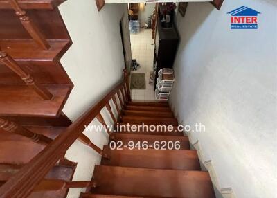 Wooden staircase with white walls leading to kitchen