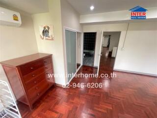 Spacious bedroom with wooden flooring and air conditioning