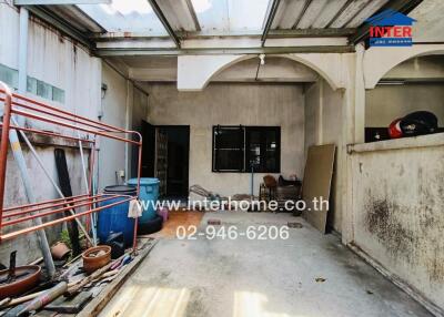 Spacious uncovered outdoor area of a building with partial roofing and visible storage items