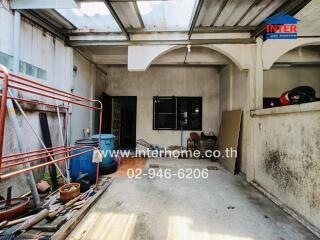 Spacious uncovered outdoor area of a building with partial roofing and visible storage items