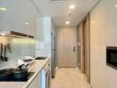 Modern kitchen with stainless steel appliances and ample lighting in a sleek apartment