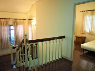 Spacious and bright hallway with wooden railings and entrance to bedroom
