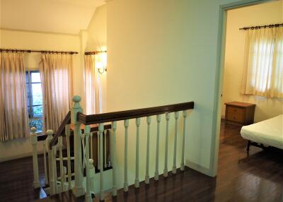 Spacious and bright hallway with wooden railings and entrance to bedroom