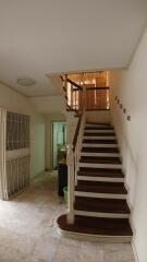 Spacious staircase area with wooden stairs and tiled flooring