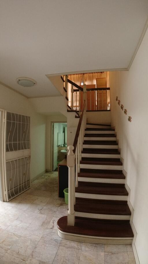 Spacious staircase area with wooden stairs and tiled flooring