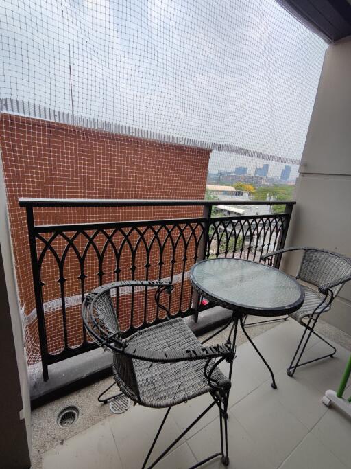 Cozy balcony with protective mesh, featuring a round glass table and two chairs