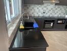 Modern kitchen with black granite countertop and stylish grey patterned backsplash