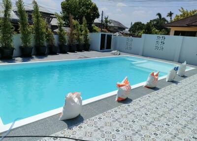 Spacious outdoor swimming pool with clean, clear water, surrounded by sun loungers and decorative plants