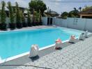 Spacious outdoor swimming pool with clean, clear water, surrounded by sun loungers and decorative plants